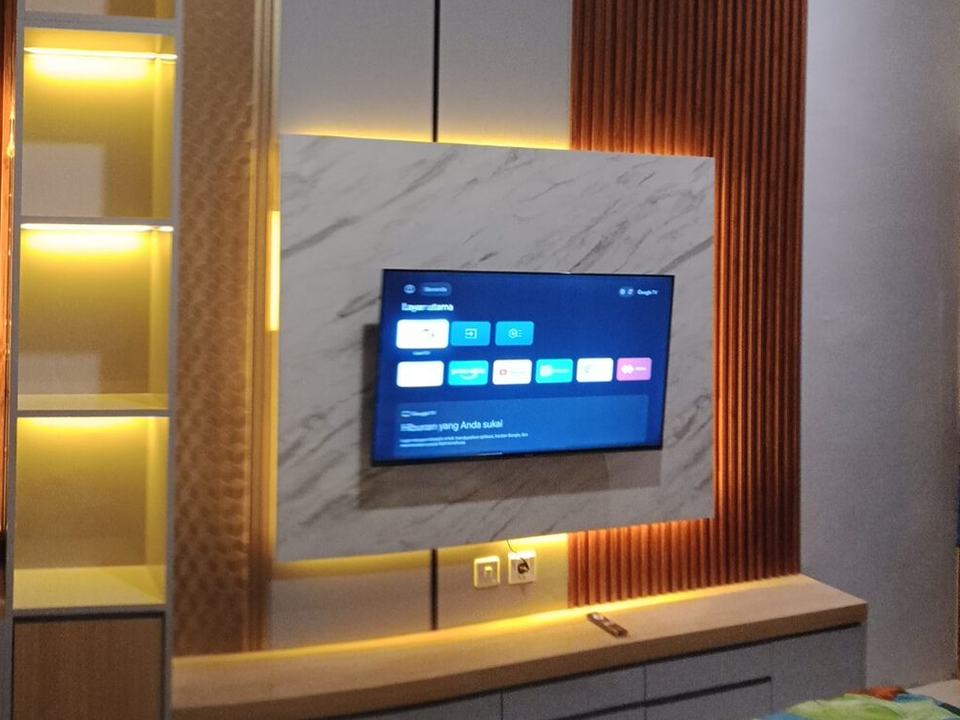 Kamar tidur dengan panel TV marmer, lis kayu, dan rak berlampu LED hasil kerja Akxatama Interior
