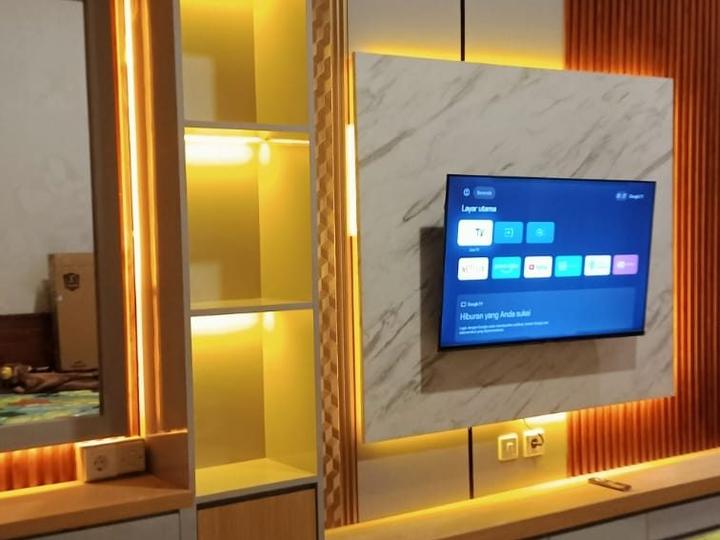 Kamar tidur ditata utuh: panel TV marmer, rak LED, dan meja rias